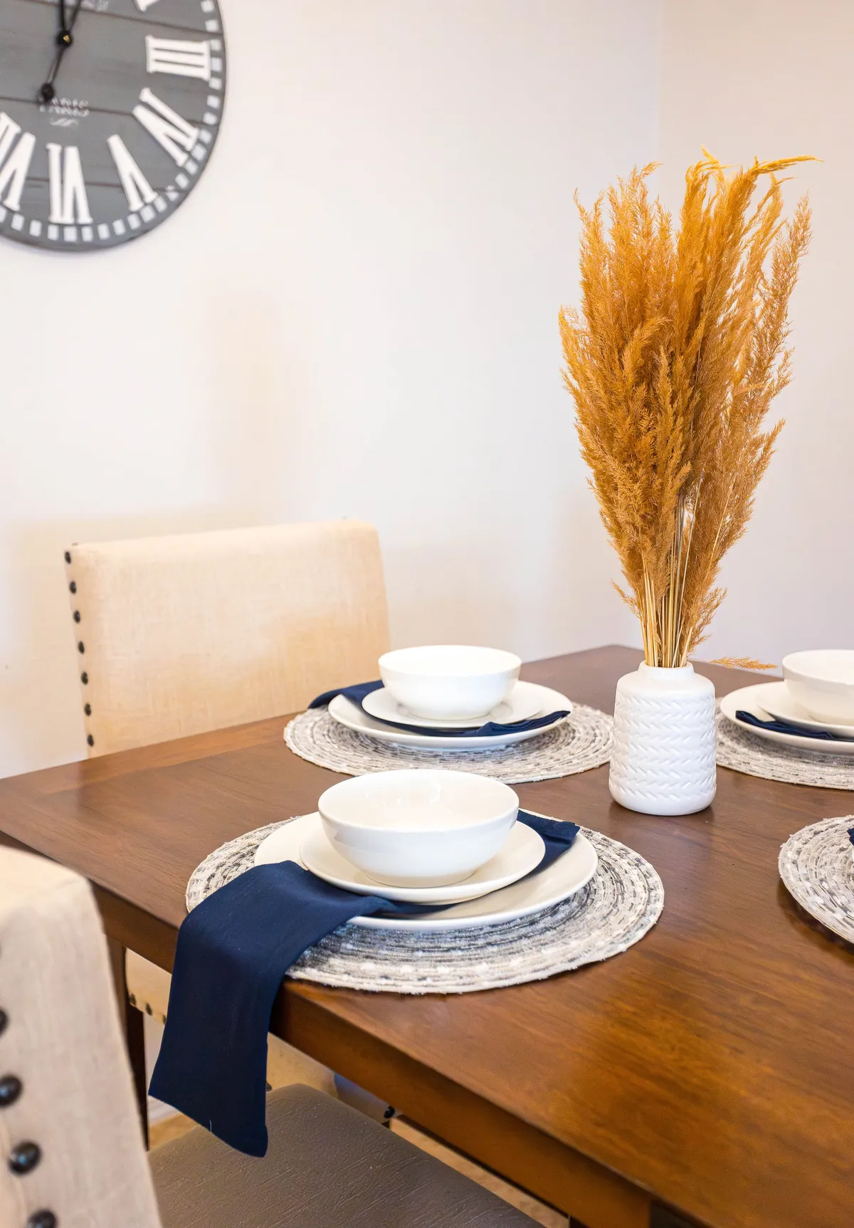 A warm, tastefully decorated dining table complete with potted dried flowers and coordinated dinnerware, evoking the feeling of shared meals and celebrations among friends or family.