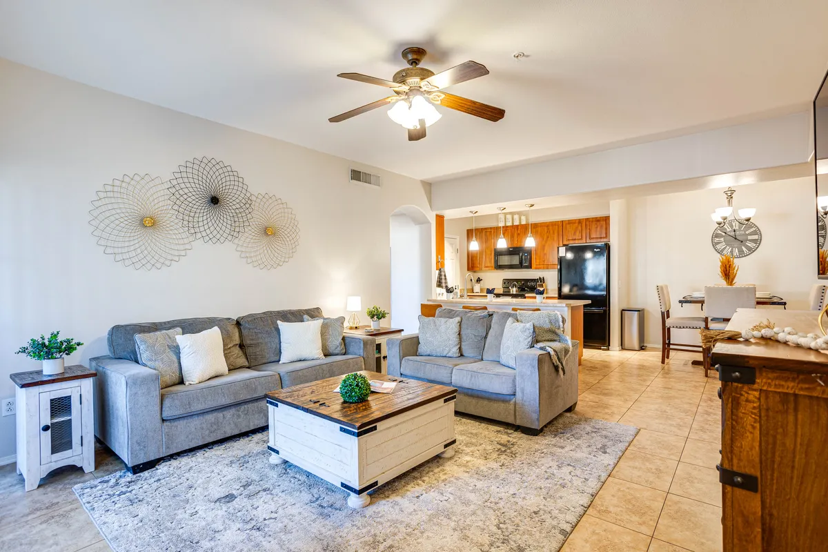 A cozy living area with a comfortable couch, coffee table, decorative wall art, and an open view toward the kitchen area. The layout is open and inviting, ideal for family gatherings, relaxing, or entertaining guests.
