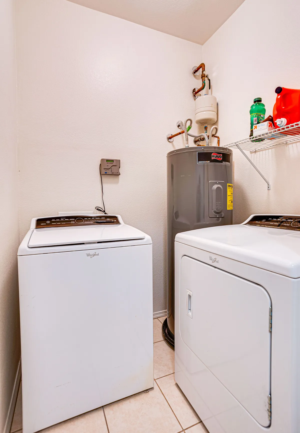 A practical laundry area with a washing machine, dryer, storage shelf, and water heater. The space is organized and functional, making chores easy during longer stays.
